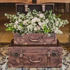 two old suitcases with flowers in them sitting on a rug next to each other