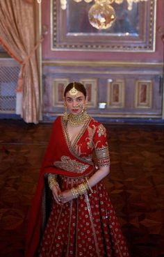 a woman in a red and gold bridal gown standing next to a chandelier