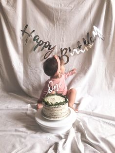 a baby sitting in front of a cake with the words happy birthday one on it