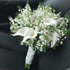 a bridal bouquet with white flowers and baby's breath in the back seat