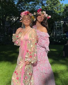 two women standing next to each other on top of a lush green field