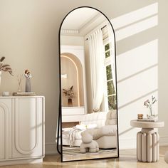 a large mirror sitting on top of a wooden floor next to a white couch and table