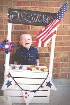 a young boy is sitting in a firework wagon with an american flag on it