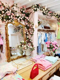 a room filled with lots of clothes and flowers on the wall next to a mirror