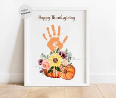 a happy thanksgiving print with flowers and pumpkins in front of a white frame on a wooden floor