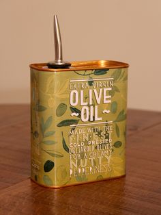 an olive oil can sitting on top of a wooden table