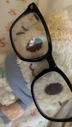 a teddy bear wearing glasses on top of a bed