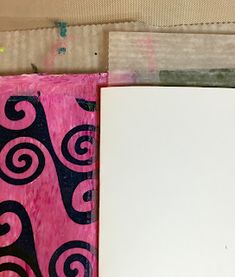 an open book with black and pink designs on it, next to a piece of paper