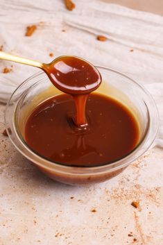 a spoon full of caramel sauce in a glass bowl