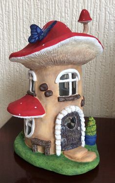 a small mushroom house with a blue butterfly on it's roof and red roof