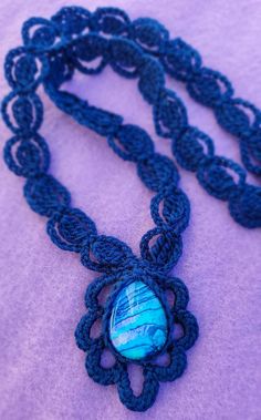 a crocheted necklace with a blue bead on it and the words lacy pendant necklace