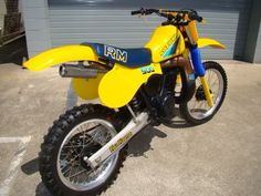 a yellow dirt bike parked in front of a garage