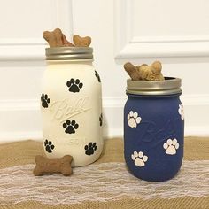 two mason jars with dog paw prints on them, one blue and the other white