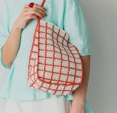 a woman holding a red and white purse