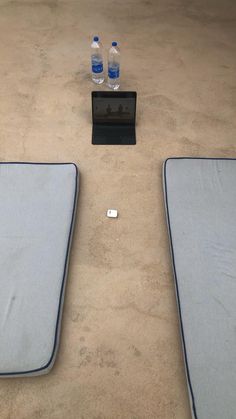 two blue mattresses sitting on top of a floor next to a bottle of water