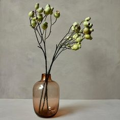 a vase with some flowers in it on a white counter top next to a gray wall