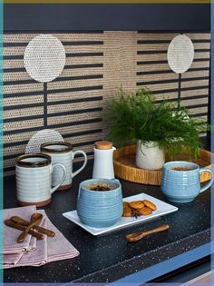 a table topped with plates and cups filled with food next to a potted plant