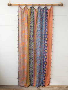 an orange and blue curtain hanging from a wooden pole in front of a white wall