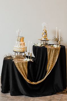 a table topped with two tiered cakes covered in gold sequins and candles