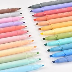 many different colored markers are lined up on a white surface with the same one in front of them