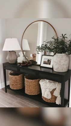 a black table with baskets on it and a mirror in the corner behind it,