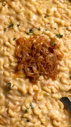 macaroni and cheese is being cooked in a skillet with a ladle