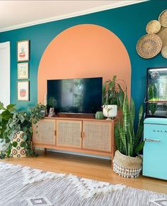 a living room filled with lots of plants next to a flat screen tv on top of a wooden cabinet