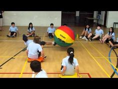 several children are sitting on the floor playing with a large ball in an indoor gym