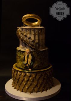 a three tiered cake with gold decorations on it