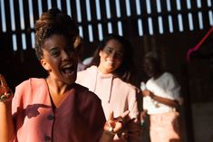 two women are laughing and holding something in their hands while another woman is standing behind them