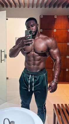 a shirtless man taking a selfie in front of a mirror with his cell phone