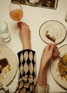 a person sitting at a table with several plates and bowls full of food on it