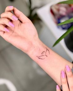 a woman's arm with a small bird tattoo on the left side of her wrist