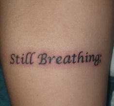 a tattoo that reads still breathing on it