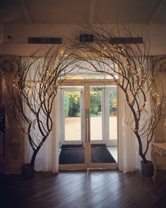 an open door with trees and lights on the outside, in front of a wooden floor