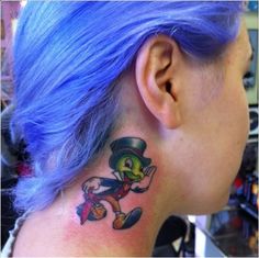 a woman with blue hair has a tattoo on her neck and behind her ear is a cartoon character