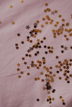 some gold and silver stars on a pink background