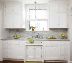 a kitchen with white cabinets and marble counter tops, along with green rug on the floor