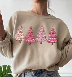 Festive pink trees add a little fun to the holiday season. Four Christmas trees across the front of the sweatshirt.  Sweatshirt sizing fits true to size.  We ship between 7 to 10 days based up on the inventory. Clothing is made to order. Made to order. Festive Long Sleeve Fall Sweatshirt, Festive Pink Crew Neck Top, Pink Festive Winter Top, Casual Festive Sweatshirt For Fall, Casual Fall Festive Sweatshirt, Pink Cotton Holiday Sweatshirt, Pink Long Sleeve Tops For Festive Occasions, Pink Long Sleeve Festive Tops, Pink Long Sleeve Christmas Sweater