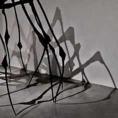 shadows cast on the wall and floor in front of a chair that is bent over