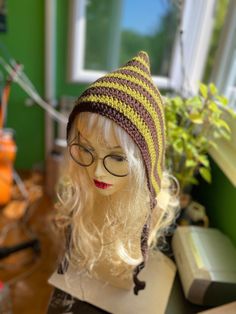 a mannequin head wearing a knitted hat and glasses on top of a table