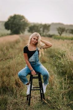 a woman sitting on top of a stool in a field