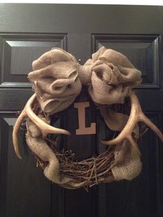 a wreath with two antlers and one letter is hanging on the front door,