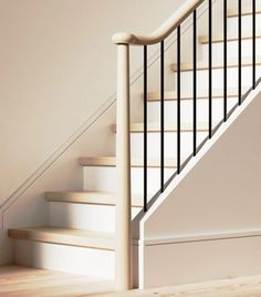 there is a white stair case next to the bannister in this room with wood floors