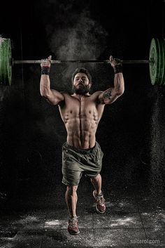 a man with no shirt is lifting a barbell