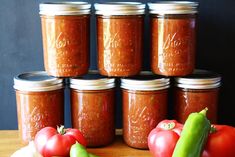 tomatoes, cucumbers and peppers sit on a table with jars of tomato sauce