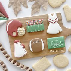 decorated cookies on a cutting board with footballs and other sports related items in the background