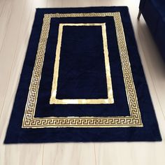 a blue area rug with gold greek border