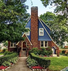 a house that is in the middle of some trees and grass with bushes around it