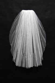 a white veil on top of a black background with the bride's dress underneath it